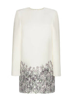 The Tilley Silk Wool Dress by Adam Lippes features an ivory hue with long sleeves, a minimalist silhouette, and a dark floral print adorning the lower half of its elegant midi-length design.