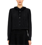 Someone wearing the Karla Blouse by Ulla Johnson, a black pleated blouse with a ruffled collar and black buttons, crafted from 100% silk, against a plain background.