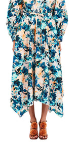 A person in a floral-patterned Madelyn Skirt by Ulla Johnson, featuring an asymmetrical hem reminiscent of a delicate floral skirt, paired with brown sandals adorned with decorative elements.