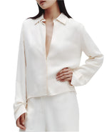 A person is elegantly dressed in TWP's Button Me Up Coated Viscose Linen Shirt paired with matching pants against a white background.