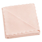 The Gooselings Cotton Knit Baby Blanket is a delicately folded, light pink knit adorned with a handstitched scalloped design and made from 100% cotton.