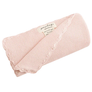 The Gooselings Cotton Knit Baby Blanket is a light pink, 100% cotton blanket with a handstitched scalloped edge, rolled with a label.