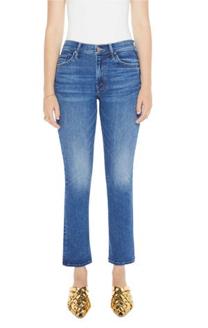 A person wears Mother’s The Insider Flood mid-blue straight-leg jeans in recycled stretch denim, paired with a white top and gold pointed shoes, standing against a white background.