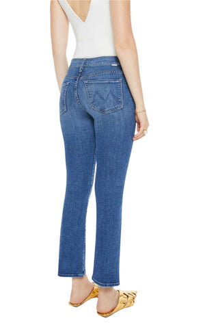 A person wearing Mother's The Insider Flood high-rise bootcut jeans in mid-blue, paired with a sleeveless white low-back top and gold flats, is shown from the back against a white background.