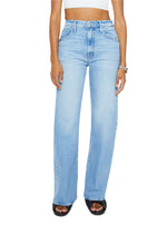 A woman wears Mother’s The Lasso Sneak light blue super high rise straight-leg jeans, a white crop top, and black open-toe shoes.