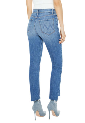 A person in Mother’s High Waisted Rider Ankle Step Fray jeans in mid-blue wash pairs them with high heels, showing off the stretch denim and "M" back pocket design as they face away from the camera.