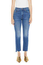 A person wearing a white top, gold woven shoes, and Mother High Waisted Rider Ankle Step Fray jeans stands against a white background.