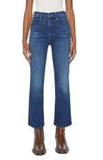 Shown from the waist down against a plain background, a person wears Mother’s The Hustler Ankle jeans with a white top and brown leather boots.