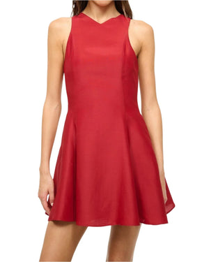 A woman wears the Staud Mini Heike Dress, a sleeveless red silk-wool blend with a fitted waist and round neckline, standing against a plain white background.