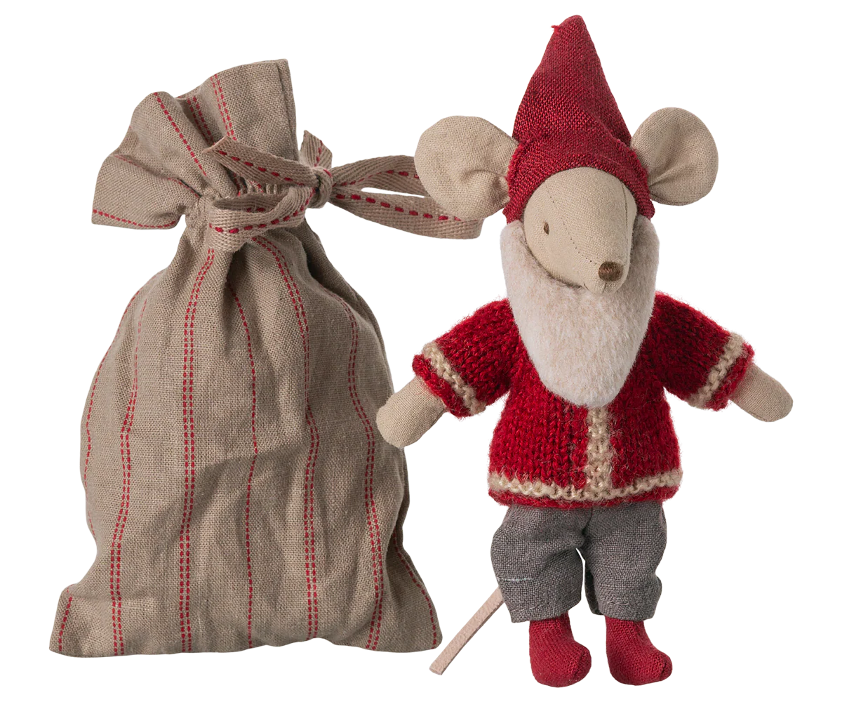 The Maileg Santa Mouse wears a red hat, red sweater, gray pants, and red shoes, and stands beside a tied beige and red striped fabric bag.