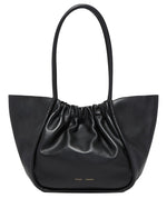 The Proenza Schouler Large Ruched Tote is a black leather handbag with a gathered design, two long handles, and a subtle logo stamp.