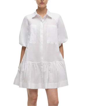 A woman wears the Simkhai Crissy Dress, a casual white mini dress featuring shirting inspiration, puffed sleeves, front pockets, and a gathered skirt.