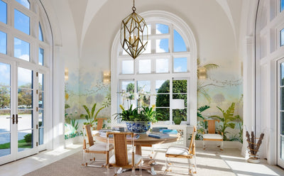 interior of mccann design group with painted landscape on walls and large arched windows, with round wooden table and lucite chairs in center