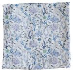 The Timo & Violet Shawl Blanket is a square cloth with a blue and purple underwater coral reef pattern, featuring fish, seaweed, octopuses, and marine motifs on a light background—ideal as a baby accessory.