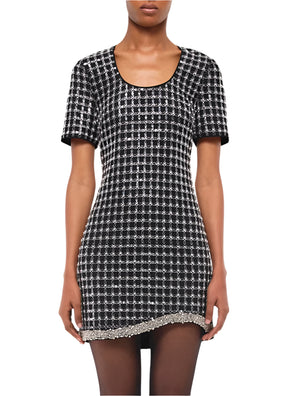 A person wearing the Simkhai Vivalie Mini Dress, a black and white checkered short-sleeve piece featuring a scoop neckline, beaded hem trim, and a relaxed fit for a flattering silhouette.