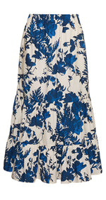 The Cara Cara Chase Skirt is made of soft cotton poplin, showcasing a white base with blue floral patterns, tiered ruffles at the hem, and an elastic waistband for extra comfort.