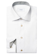 A folded Eton Slim Cut Away Medallion Effect Signature Twill Shirt in white features beige buttons, a patterned inner collar and cuff, and the "Eton" label inside the collar.