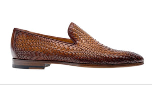 The Magnanni Herrera Woven Loafer, a hand-woven brown leather shoe with a flat heel, is elegantly displayed in a side view against a pristine white background.