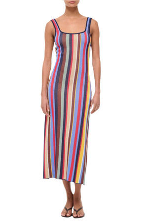 A person wearing the Staud Katie Dress, a sleeveless compact knit midi with vertical multicolored stripes, and black sandals, stands against a white background.