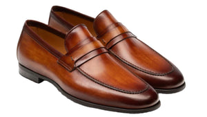 The Daniel Loafer by Magnanni, featuring a classic penny loafer design with polished brown leather, low heel, and edge stitching, is displayed against a white background.