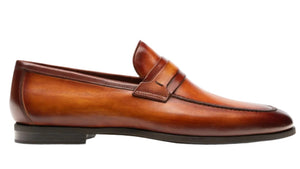 The Daniel Loafer by Magnanni is a classic penny loafer crafted in rich brown leather, featuring a sleek penny strap atop the smooth upper. Highlighted against a white background, it offers Línea Flex technology for all-day comfort, blending sophistication with timeless style.