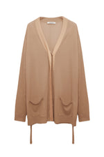The Shimmering Merino Cardigan by Dorothee Schumacher is beige with long sleeves, a V-neck, metallic foil trim, dual pockets, and tie details at the hem.