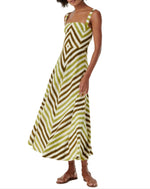 Elegantly dressed in the sleeveless Margherita Ikat Stripes Dress by Emporio Sirenuse, featuring green and brown diagonal stripes handloomed in cotton, the look is complete with stylish brown sandals on a crisp white background.