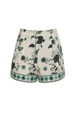 The Trish Shorts by Cara Cara are white with a green floral print, featuring an elastic waistband and decorative trim along the hem.
