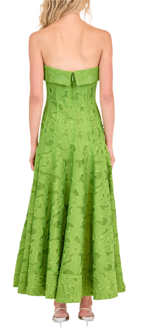 A woman wearing the Simkhai Imogen Midi Dress in Kiwi—a strapless, ankle-length summer jacquard with a textured floral pattern—stands with her back to the camera.