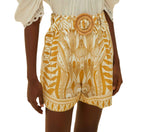 Someone is wearing Farm Rio Lace Nature Off-White Shorts, crafted from eco-responsible fibers with a round belt buckle, styled with a white puff-sleeve blouse.