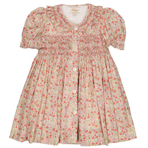 The Kidiwi Baby Girls' Adeline Smocked Dress showcases a floral-patterned, short-sleeved design with a ruffled collar and bodice smocking in pink and green hues, accented by a delicate blue flower print.