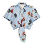 The Cara Cara Asbury Top is a light blue cropped blouse with a delightful floral print and a charming front tie, ideal for any casual outing.