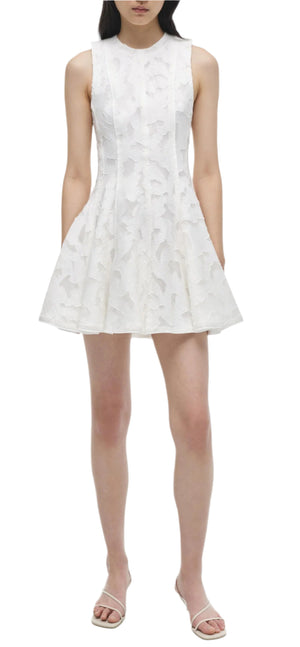 The Sylvia Mini Dress by Simkhai is sleeveless with a white textured fabric and a flared skirt, ideal for sunny days. Pair it with white strappy sandals for an effortless Summer Jacquard look.