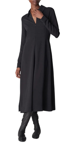A person in a CO Long Sleeve Crepe Shirt Dress, a black midi-length with a collar, styled elegantly with knee-high boots. The stretch viscose fabric of the dress drapes beautifully, exuding effortless charm.