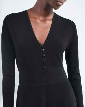 A person wearing the Maria McManus Button Front Dress, featuring long sleeves, a deep V-neck, and elegant corozo nut buttons down the front.