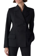 A model wearing CO's Double Breasted Fitted Blazer in black, crafted from lightweight virgin wool with wide lapels and matching pants, hand in pocket. White background.