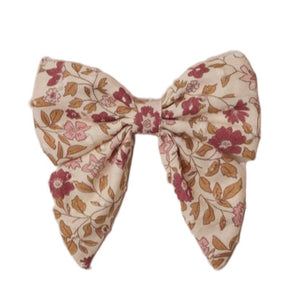 The Noralee Norah Bow is a fabric hair clip featuring a beige background with pink and brown floral accents, secured with a rose gold alligator clip for timeless, stylish wear.