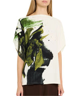 A person wearing a Jason Wu Collection Asymmetrical Printed Crepe Boatneck Top, featuring artistic green and black asymmetrical brushstrokes on the back, paired with dark pants.
