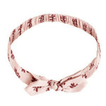 The Rylee & Cru Baby Bow Headband is a light pink fabric headband with a small floral pattern, knotted bow at the front, and soft scrunchy elastic band for comfort.