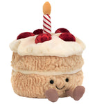 The Jellycat Amuseables Birthday Cake is a plush slice with a smiling face, soft strawberries, white icing, and a red-and-white striped candle—perfect for birthday celebrations.