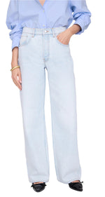 Person wearing a light blue button-up shirt tucked into Anine Bing's Manon Jean—ultra-bleached, high-waisted wide-leg jeans—paired with black pointed-toe shoes for a modern baggy silhouette.