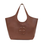 The Anine Bing Medium Lili Tote is a chic and practical brown leather bag, crafted from pebbled leather with two handles and a round embossed logo on the front, embodying the signature ANINE BING style for everyday elegance.