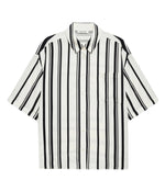 The Anine Bing Coco Shirt Monogram Stripe is a boxy collared shirt in a lightweight cupro blend with ivory and black vertical stripes, short sleeves, and a chest pocket, shown laid flat on a white background.