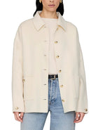 A woman wears the Anine Bing Luca Cashmere Blend Jacket in cream over a light sweater, styled with blue jeans.