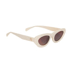 The Anine Bing Roma Sunglasses feature cream-colored cat-eye frames in bone acetate with brown gradient lenses and a small gold logo on the temple, shown against a white background.