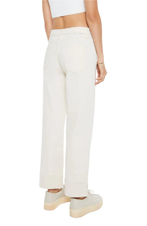 A person wearing the Mother Spitfire Ankle Cuff off-white oversized jeans, a white cropped top, and beige platform sneakers, shown from the back.