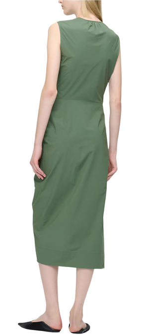 A person is seen from behind wearing Callas Milano's Agnes Dress, a sleeveless green wrap midi crafted from luxurious Italian cotton, paired with black shoes.