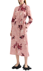 A person wears the Erdem Long Sleeve Abstract Rose Shirt Dress in pink cotton poplin with maroon rose prints, styled with black fringed shoes.