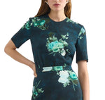 Model in Erdem’s Short Sleeve Abstract Rose Top, featuring dark blue fabric with green and white abstract roses, short sleeves, and a fitted waist; shown from shoulders to mid-thigh.