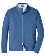 The Contour Jacket by Peter Millar is a lightweight blue zip-up with a standing collar. It has two front zipper pockets, made from water-resistant technical fabric. A white lining at the top adds subtle contrast.